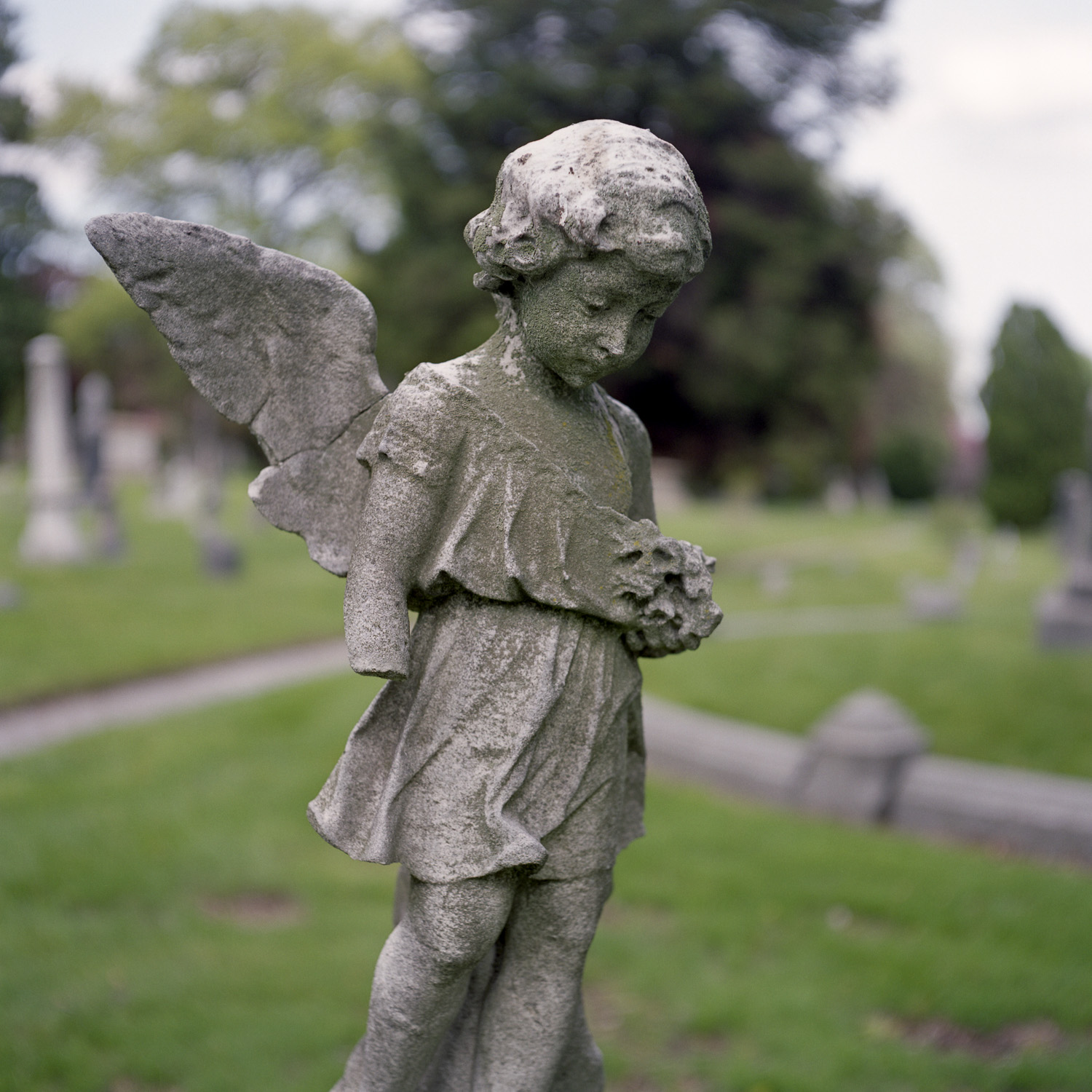 Color image of standing weathered stone statuary cherub.