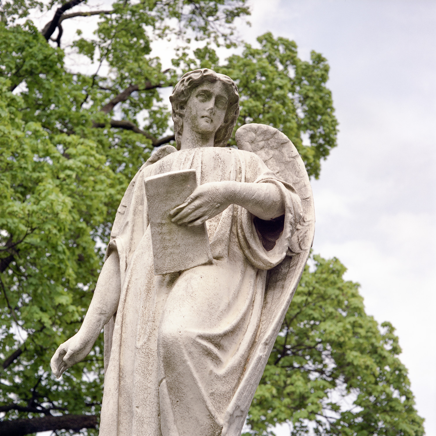 Color image of a winged stone statuary holding a stone tablet.