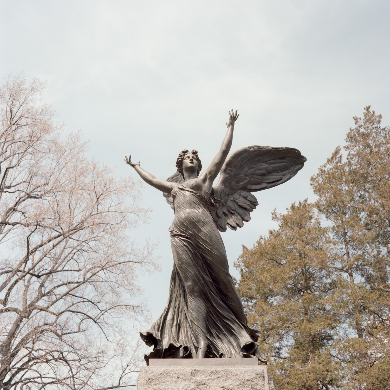 Color image of a winged bronze statuary with outstretched arms