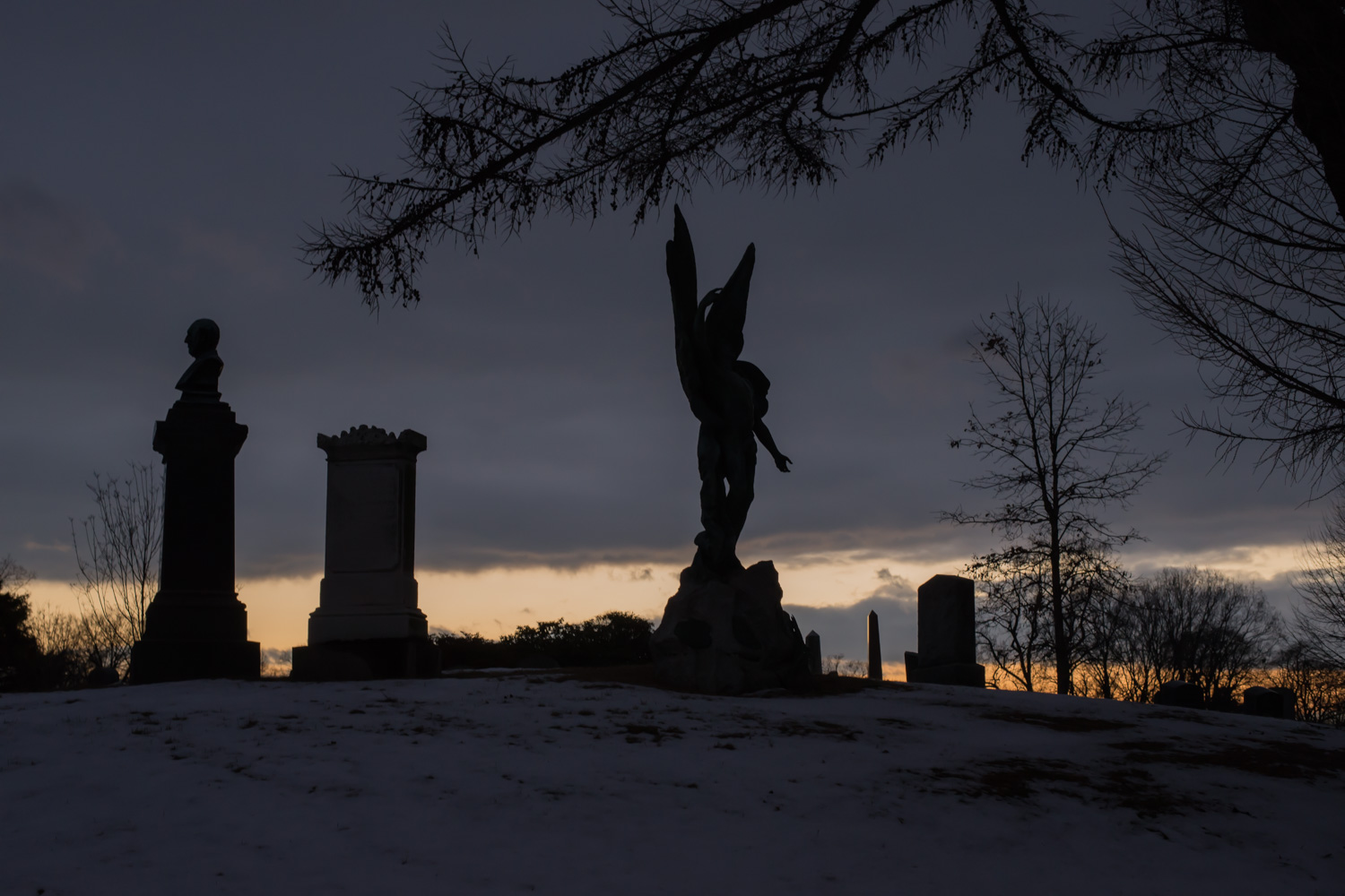 Color image of a bust and winged statuary silhouetted at Sunrise in Winter.