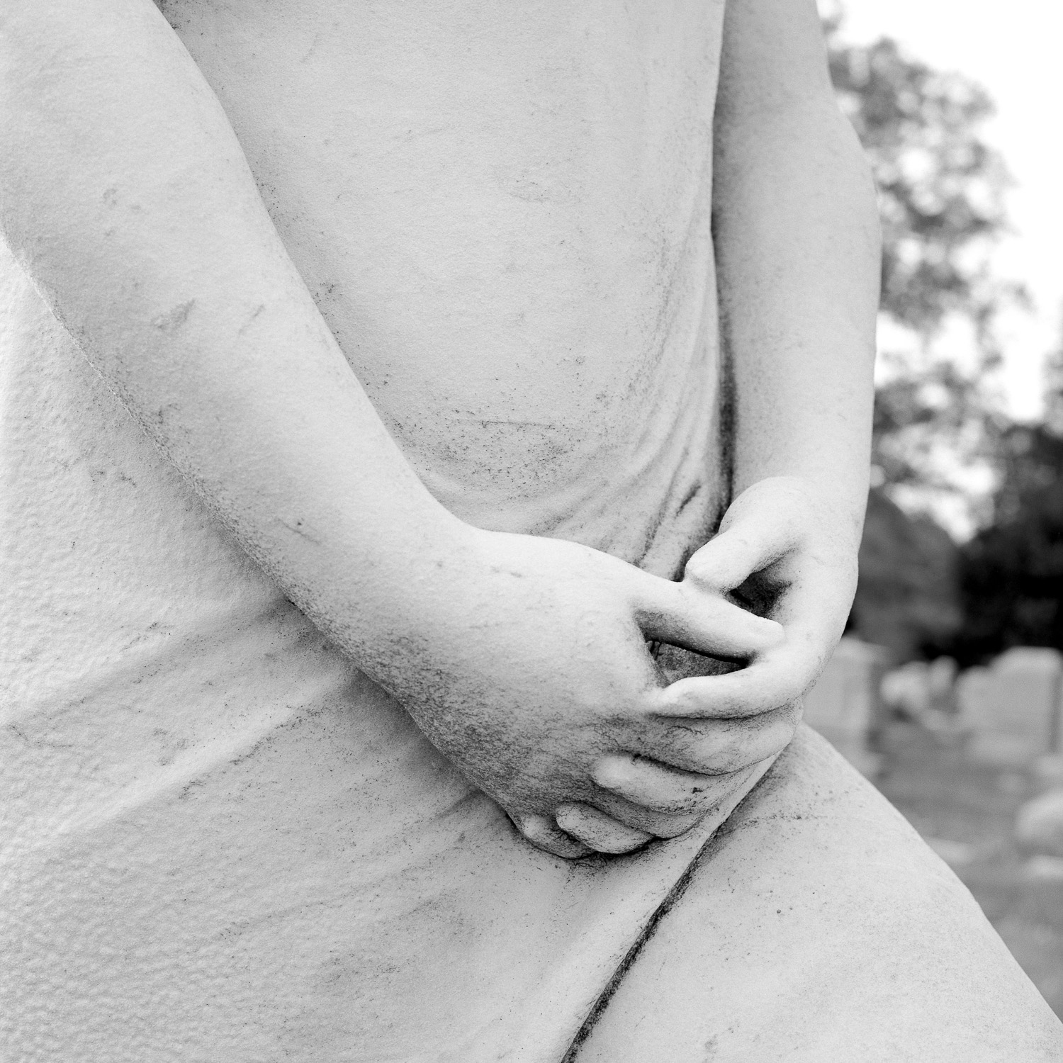 B&W image of a close-up of a white statuary's folded hands.