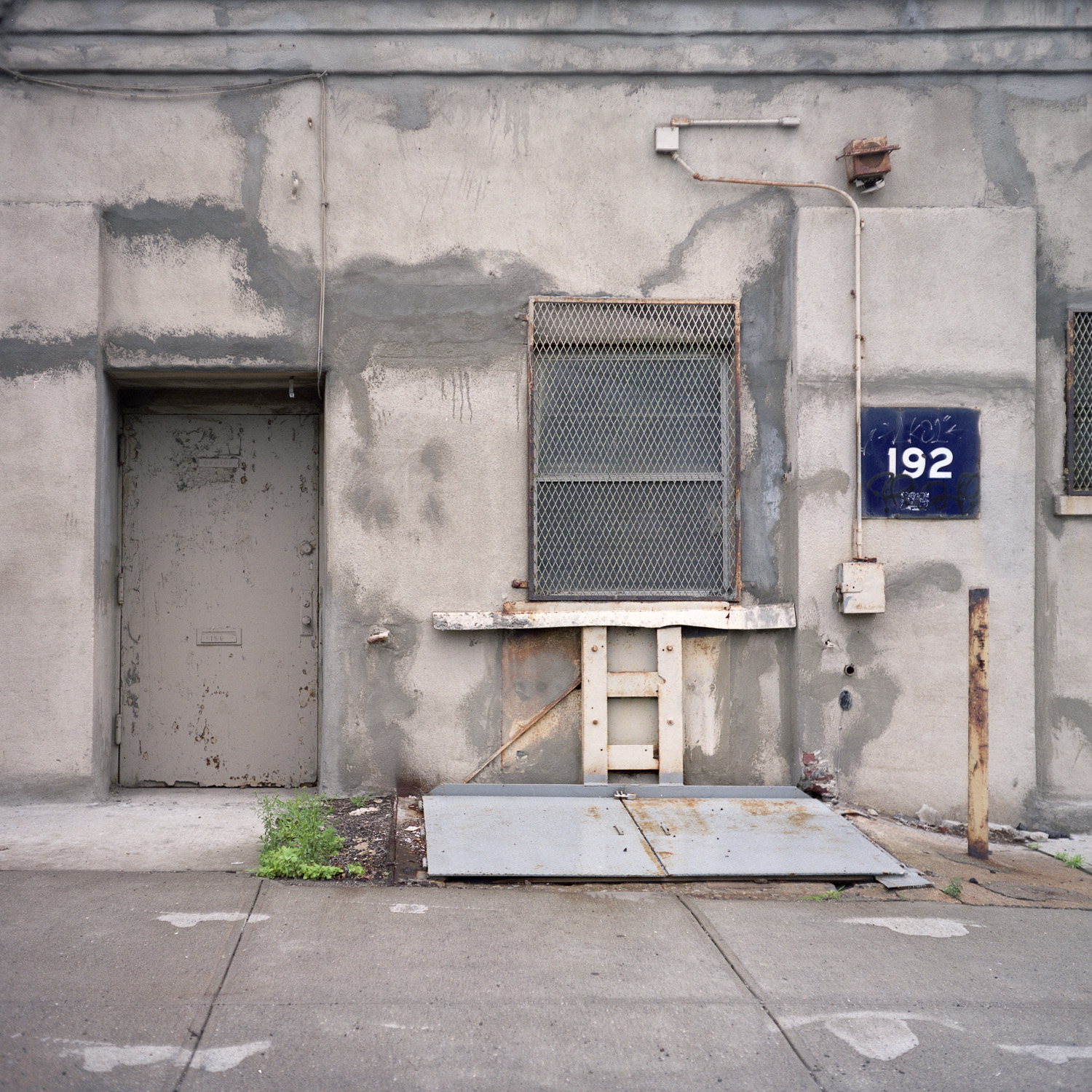 Color image of concrete front of building with many patches labeled '192'.