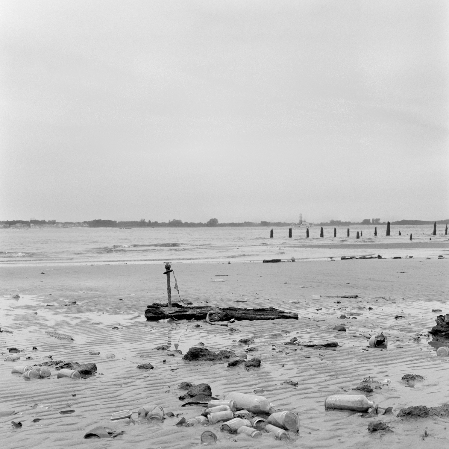 B&W image of bottles and trash on a beach.