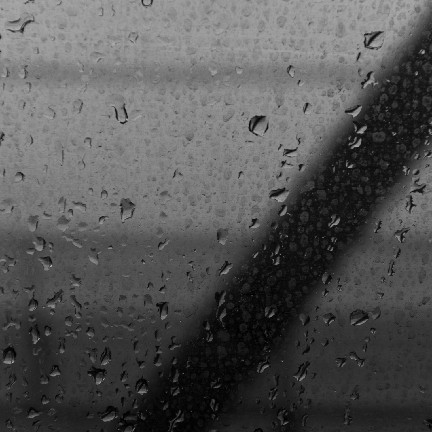 B&W image close-up of rain on a dirty subway window.