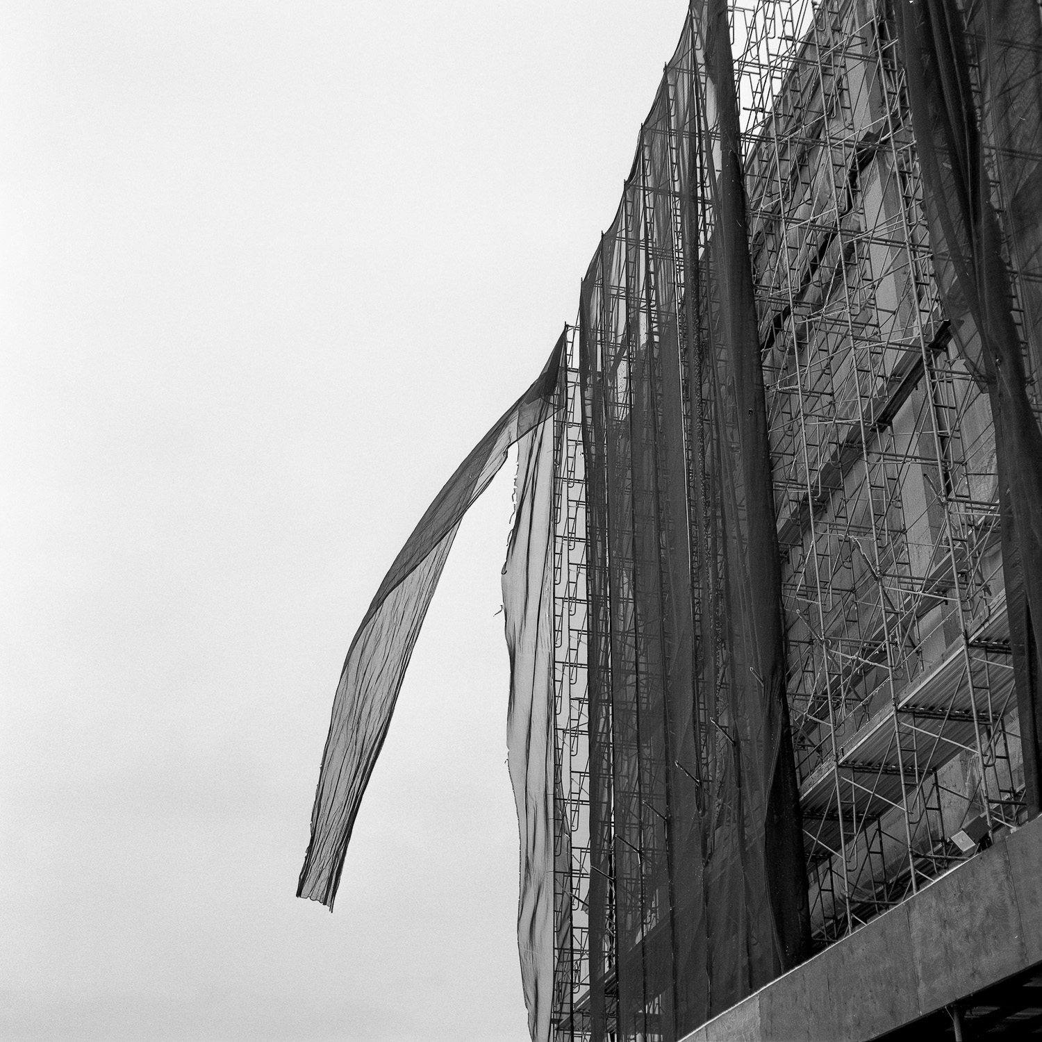 B&W image of netting blowing off of a scaffolding.