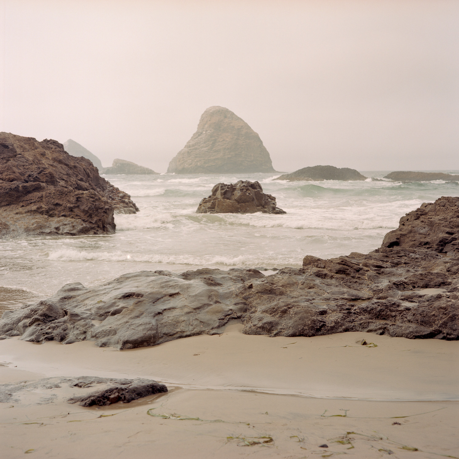 Color image of volcanic rock on a misty beach.