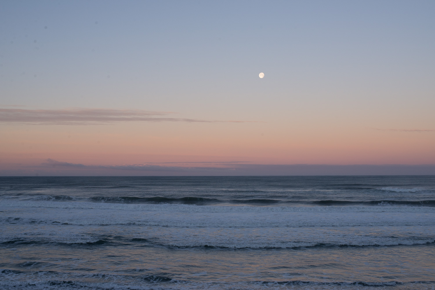 Color image of the moon rising over the Pacific Ocean just after sunset.