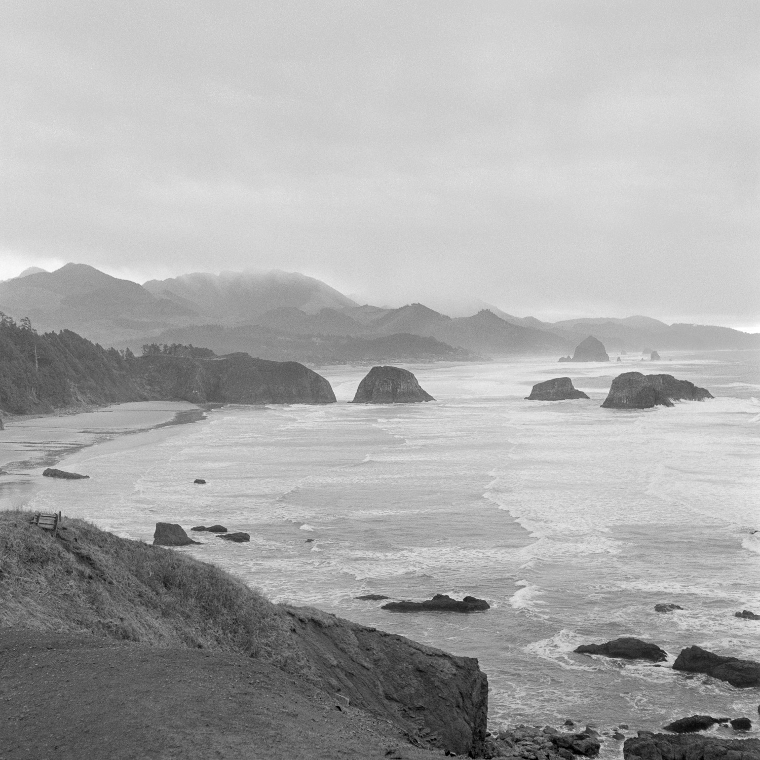 B&W image of a misty Oregon Coast line dotted with large rocks.